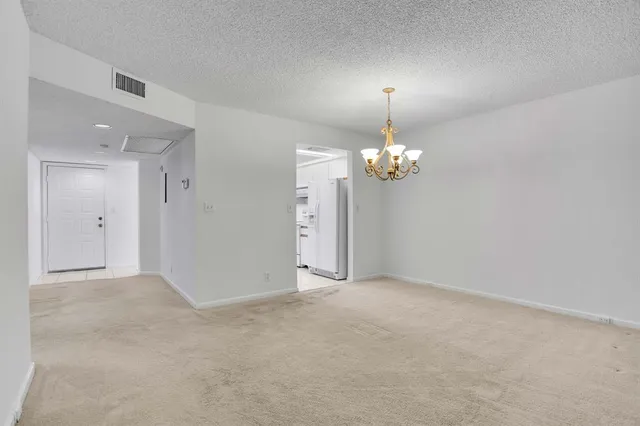a view of an empty room with chandelier fan