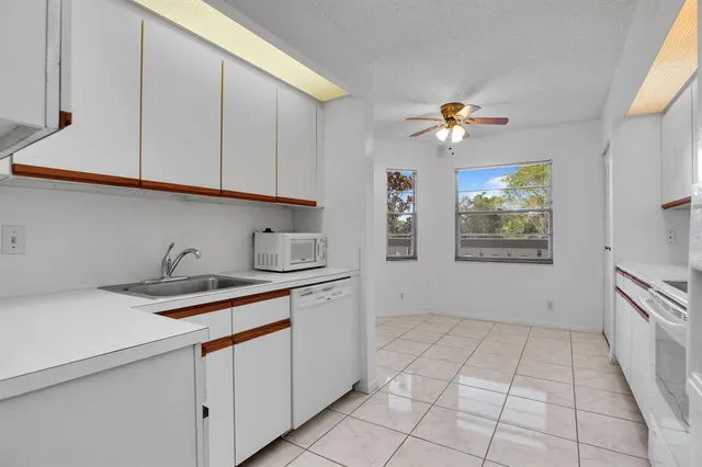 a kitchen with granite countertop a stove a sink and dishwasher with white cabinets