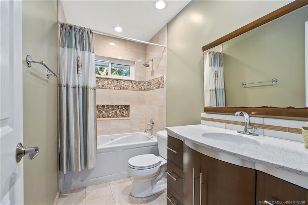 4599 Southeast Halston Court Stuart, FL 34997 - Photo 30 of 65 a bathroom with a bathtub shower sink vanity mirror and toilet