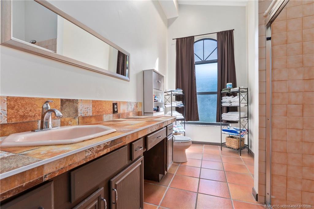 4599 Southeast Halston Court Stuart, FL 34997 - Photo 38 of 65 a spacious bathroom with a granite countertop sink a mirror and a shower