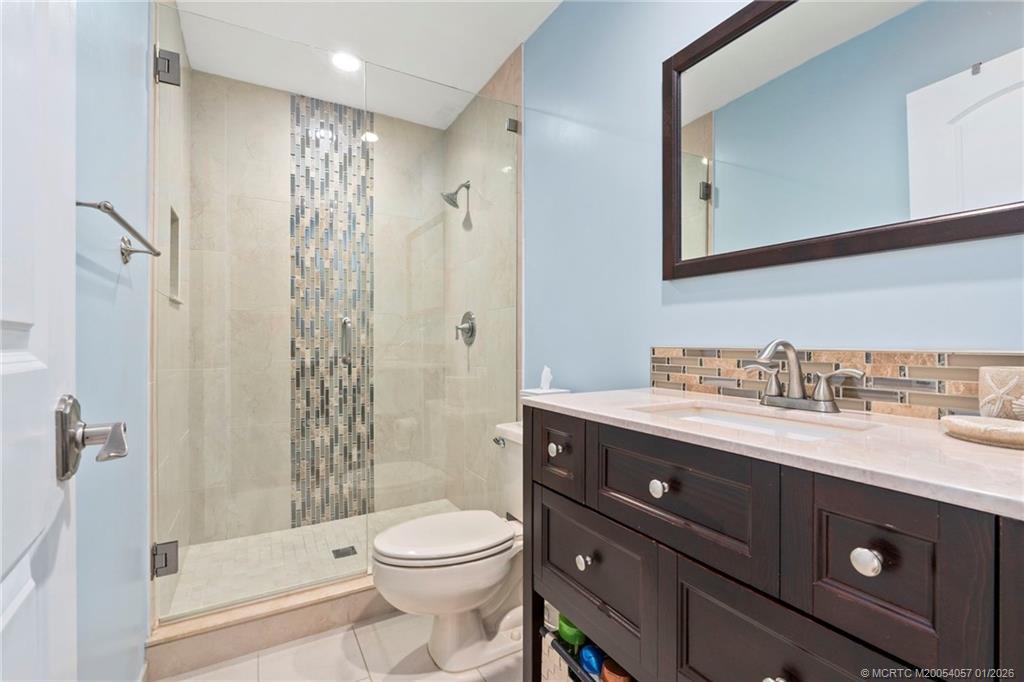 4599 Southeast Halston Court Stuart, FL 34997 - Photo 42 of 65 a bathroom with a granite countertop sink toilet a mirror a vanity and shower