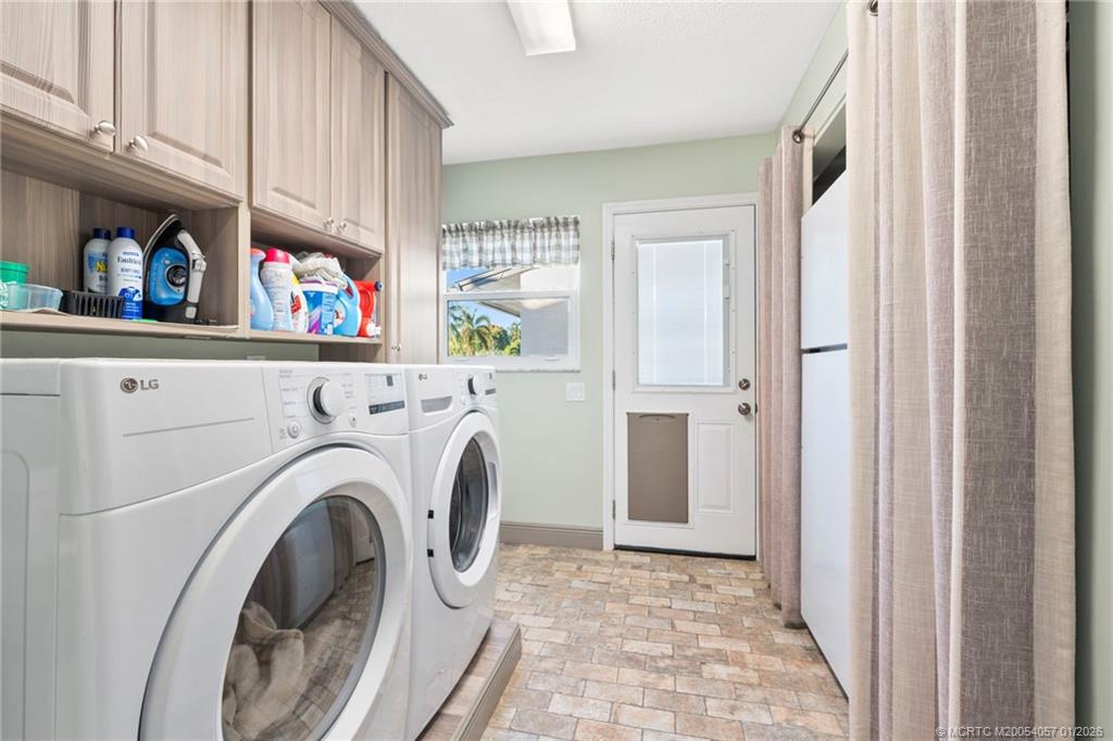4599 Southeast Halston Court Stuart, FL 34997 - Photo 43 of 65 a view of washer and dryer with kitchen in the background