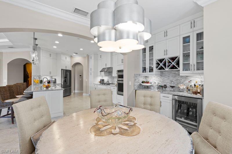 16391 Viansa Way, Unit 101 Naples, FL 34110 - Photo 13 of 49 a kitchen with stainless steel appliances kitchen island granite countertop a stove a sink a kitchen island with chairs and cabinets