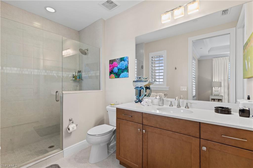 16391 Viansa Way, Unit 101 Naples, FL 34110 - Photo 30 of 49 a bathroom with a toilet sink vanity and mirror