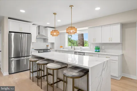 a kitchen with stainless steel appliances granite countertop a table chairs sink refrigerator and microwave