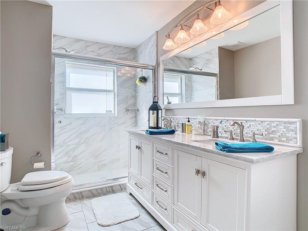 147 Plantation Circle Naples, FL 34104 - Photo 20 of 32 a bathroom with a granite countertop toilet sink and a mirror