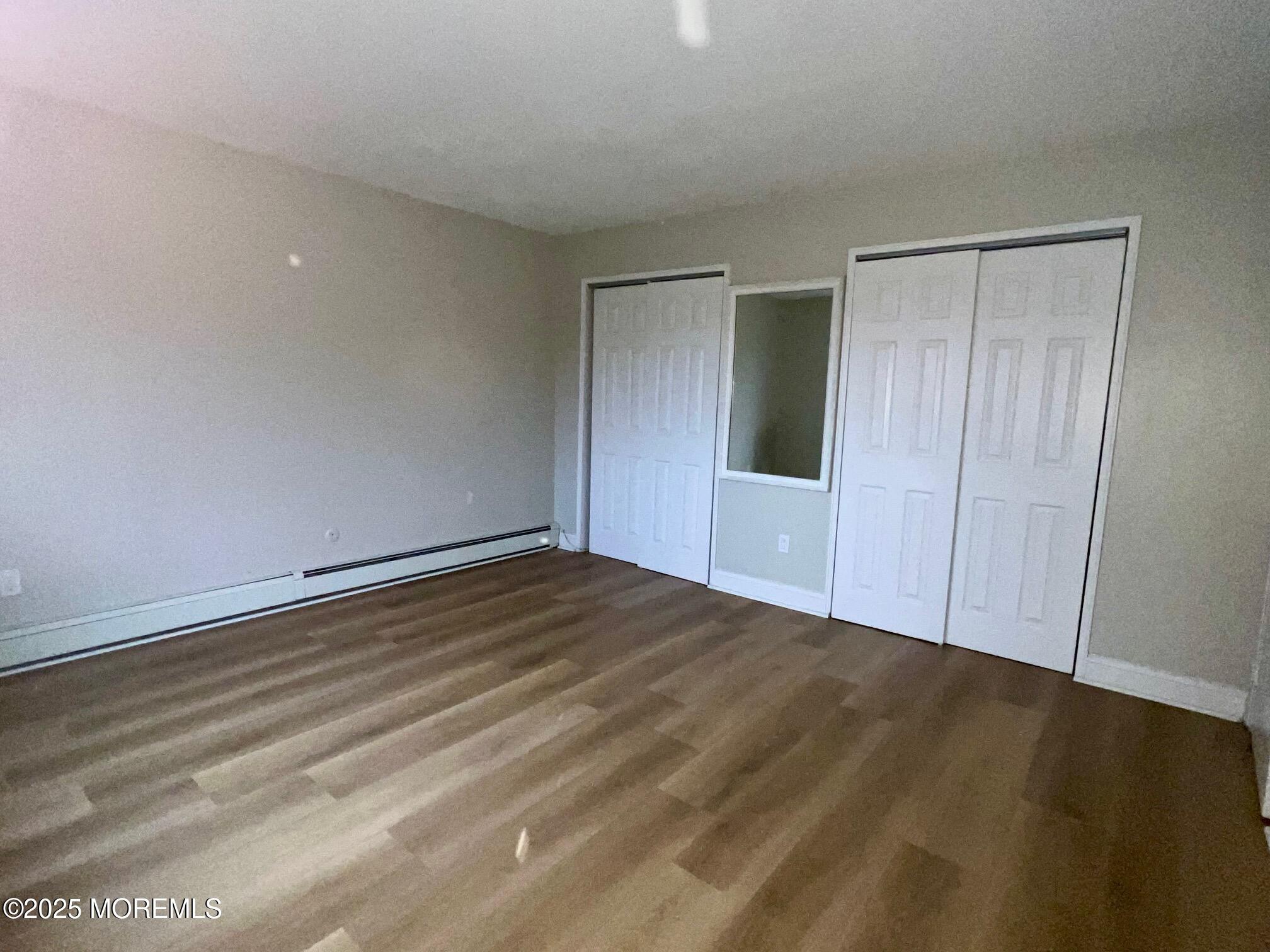 12 Manchester Court, Unit H Freehold, NJ 07728 - Photo 6 of 11 a view of an empty room with wooden floor and closet