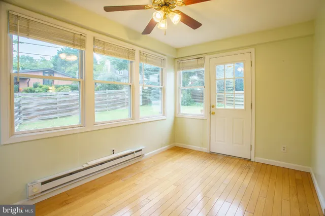 a view of an empty room with a window and wooden floor
