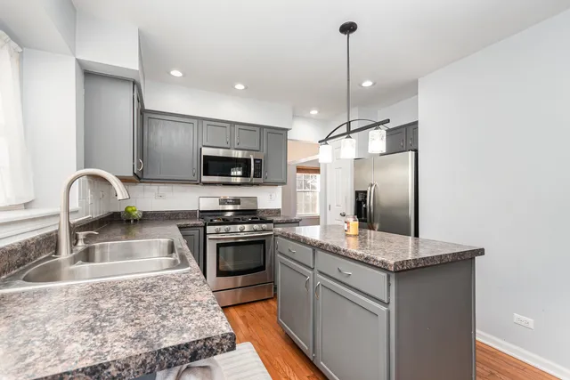 a kitchen with kitchen island granite countertop stainless steel appliances a sink stove and refrigerator