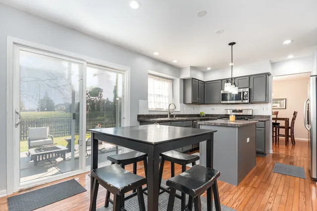 a kitchen with stainless steel appliances granite countertop table chairs and wooden floor
