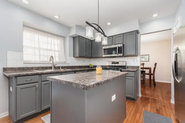 a kitchen with stainless steel appliances granite countertop a sink a stove a microwave a center island and a window
