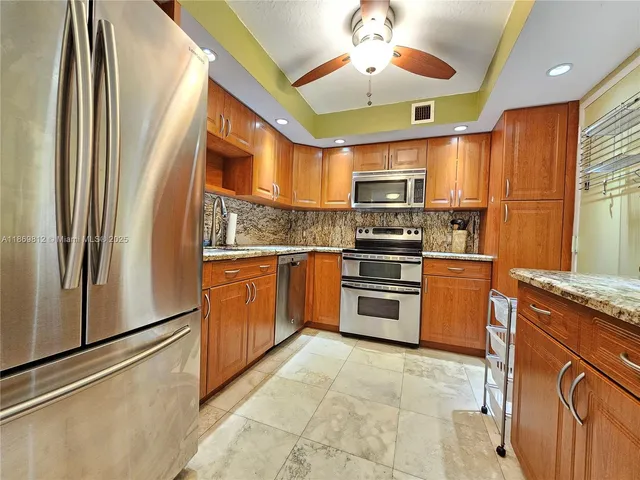 a kitchen with stainless steel appliances granite countertop a refrigerator a stove and a sink with cabinets