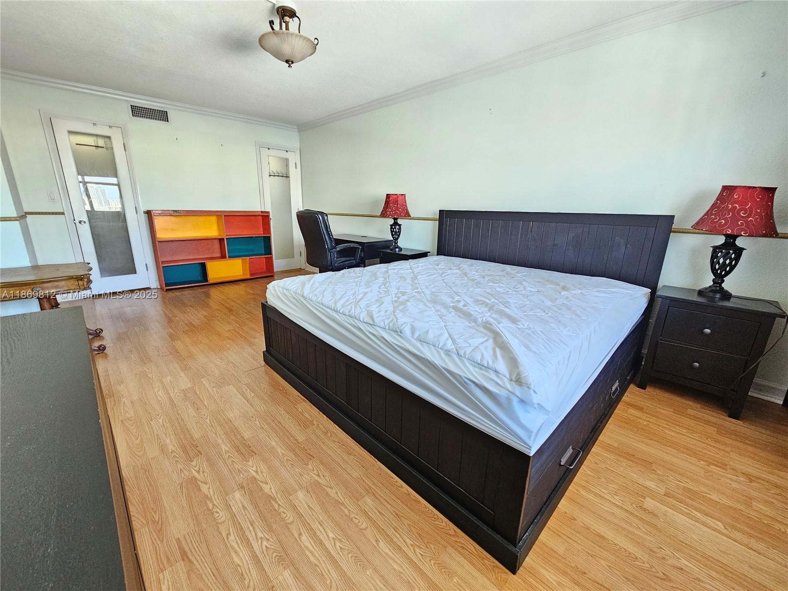 427 Golden Isles Drive, Unit 16E Hallandale Beach, FL 33009 - Photo 7 of 17 a bedroom with a bed and wooden floor