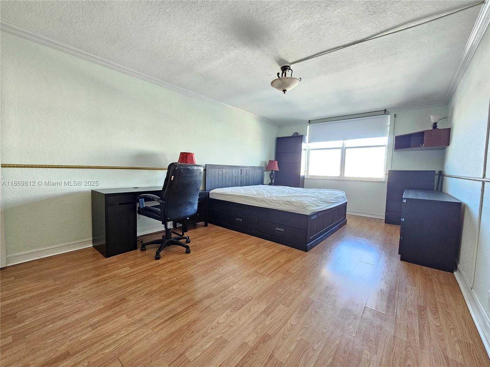 427 Golden Isles Drive, Unit 16E Hallandale Beach, FL 33009 - Photo 8 of 17 a bedroom with a bed and a chair