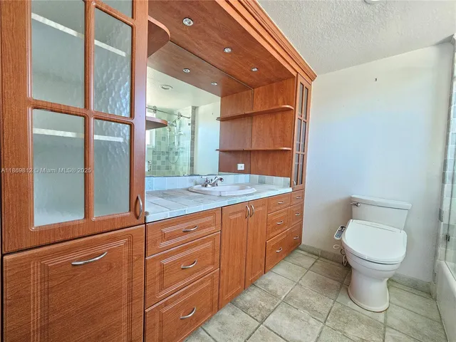 a bathroom with a granite countertop sink mirror vanity and toilet