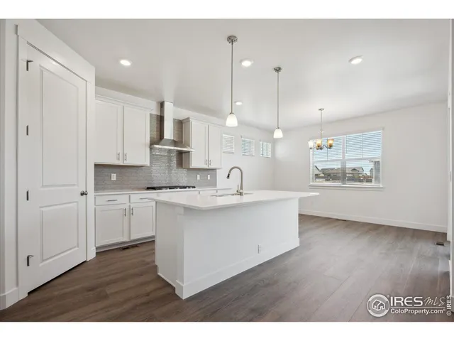 a open kitchen with kitchen island a sink dishwasher a stove and white countertops with wooden floor