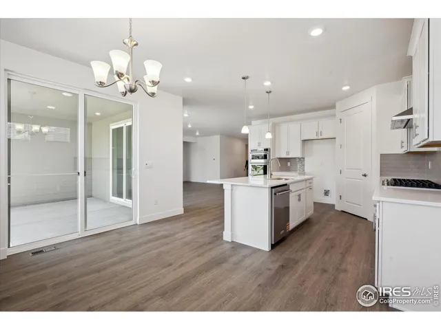 a open kitchen with a refrigerator a sink dishwasher a stove and white cabinets with wooden floor