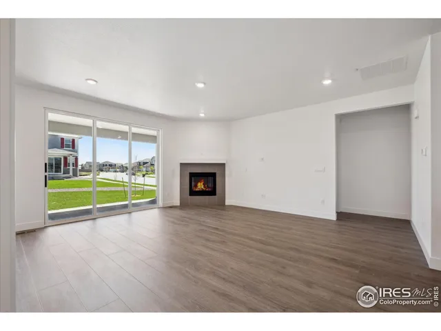 a view of an empty room with wooden floor and a fireplace