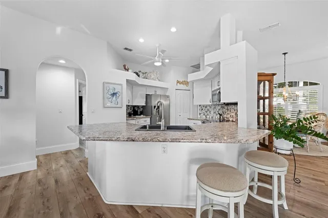 a dining hall with stainless steel appliances granite countertop a dining table and chairs with wooden floor