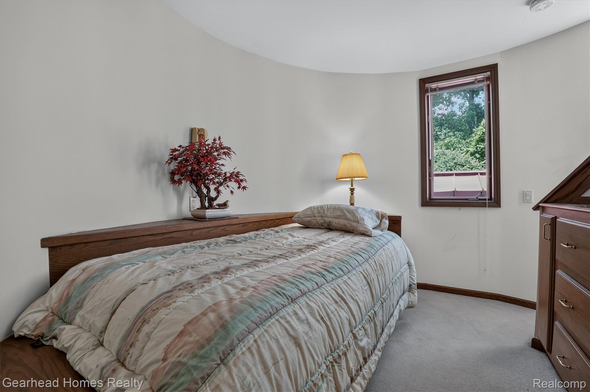 3486 West Drahner Road Oxford, MI 48371 - Photo 12 of 51 Bedroom featuring a curved wall, built-in wood-finish headboard, and a single window with exterior landscaping visible