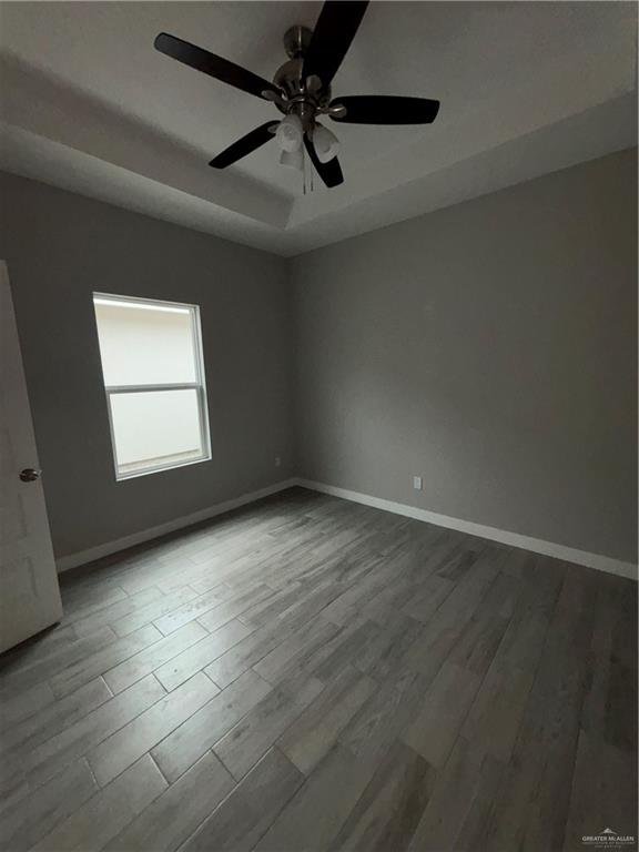 3186 Briggs Road, Unit 2 Weslaco, TX 78596 - Photo 14 of 19 an empty room with wooden floor ceiling fan and windows