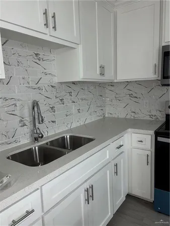 a view with granite countertop white cabinets sink and dishwasher