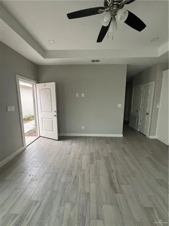 an empty room with wooden floor ceiling fan and windows