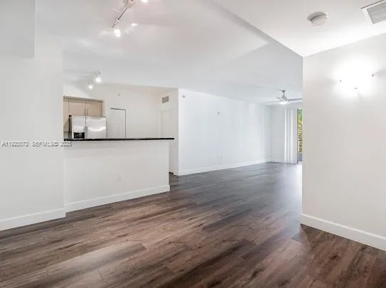 a view of a kitchen with a refrigerator and wooden floor