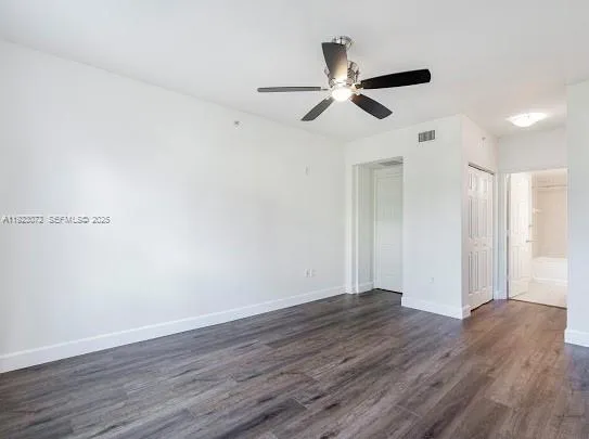 an empty room with wooden floor fan and windows