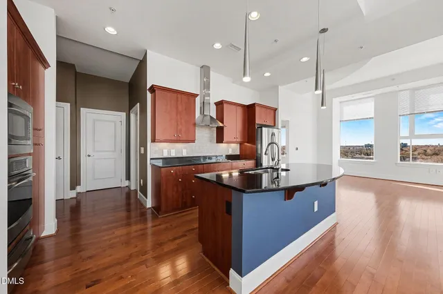 a kitchen with kitchen island granite countertop wooden floors and a sink