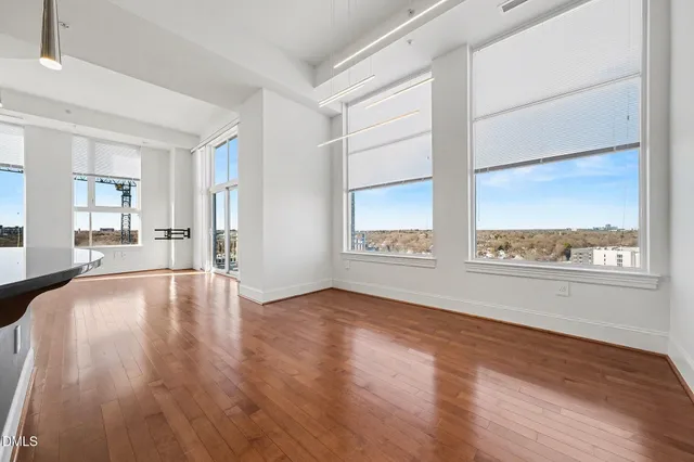 a view of an empty room with a window and wooden floor