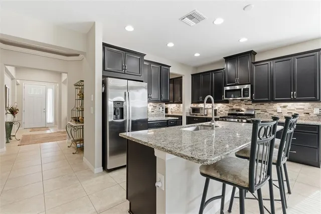 a kitchen with stainless steel appliances kitchen island granite countertop a refrigerator and a stove top oven