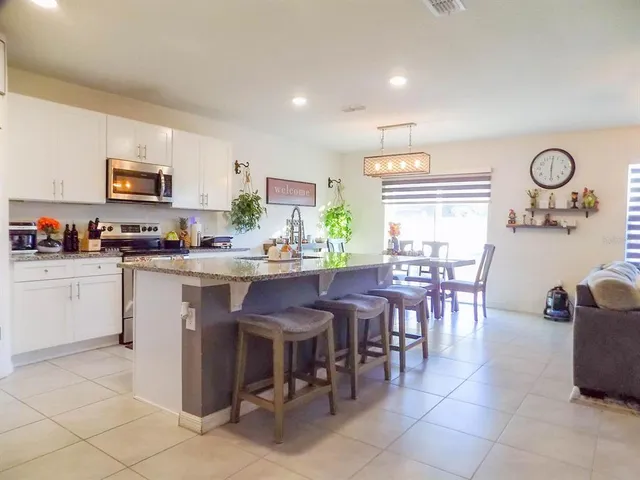 a kitchen with stainless steel appliances granite countertop a stove a sink a dining table and chairs