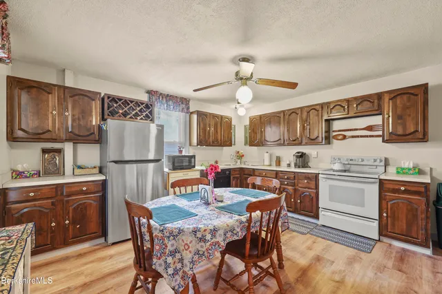 a kitchen with stainless steel appliances a stove a refrigerator a sink a dining table and chairs