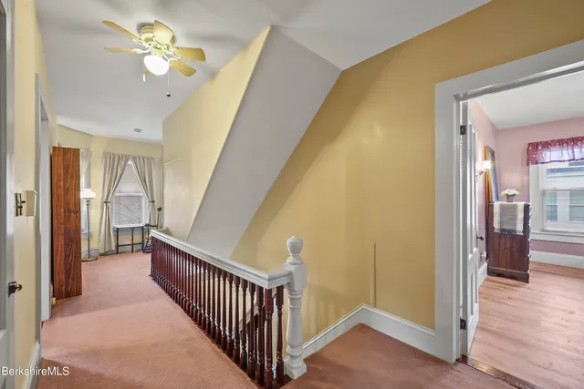 a view of a hallway with a chandelier fan and wooden floor