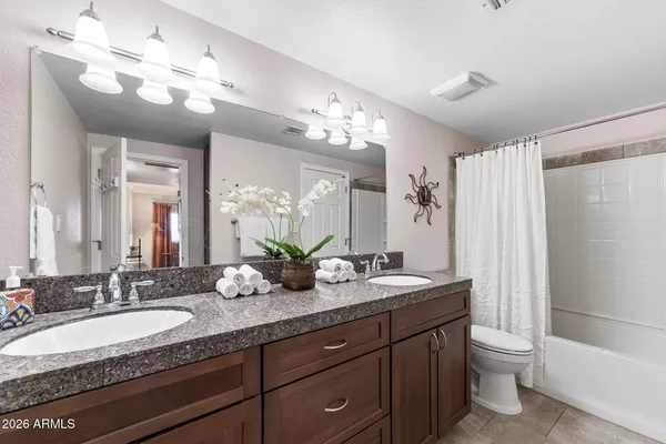 a bathroom with a granite countertop sink a toilet and a large mirror