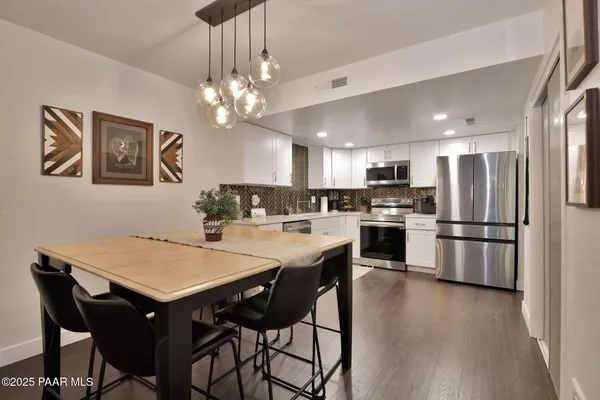 a kitchen with stainless steel appliances a dining table chairs and refrigerator