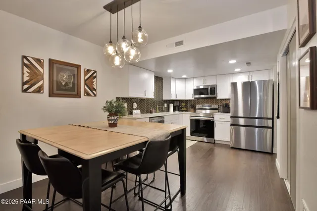 a kitchen with stainless steel appliances a dining table chairs and refrigerator