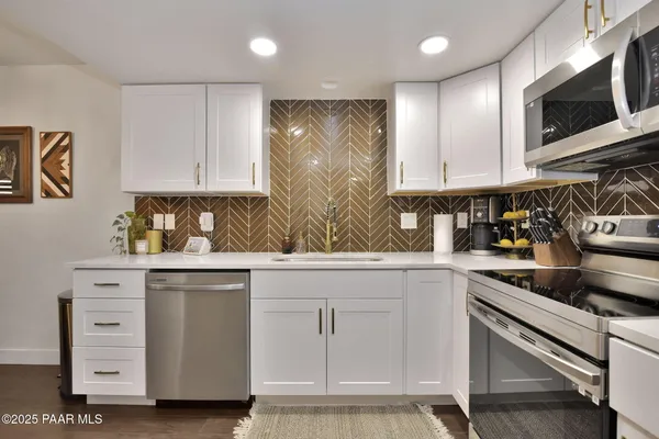 a kitchen with white cabinets and sink
