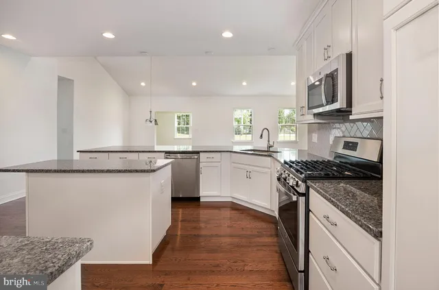 a kitchen with granite countertop a stove a sink and a microwave