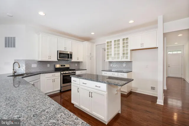 a kitchen with granite countertop a stove a sink and a refrigerator