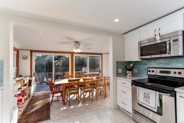 a open kitchen with stainless steel appliances granite countertop a stove top oven a sink dishwasher a dining table and chairs with wooden floor