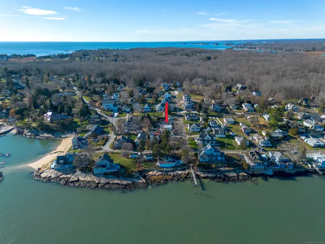 an aerial view of ocean and residential houses with outdoor space