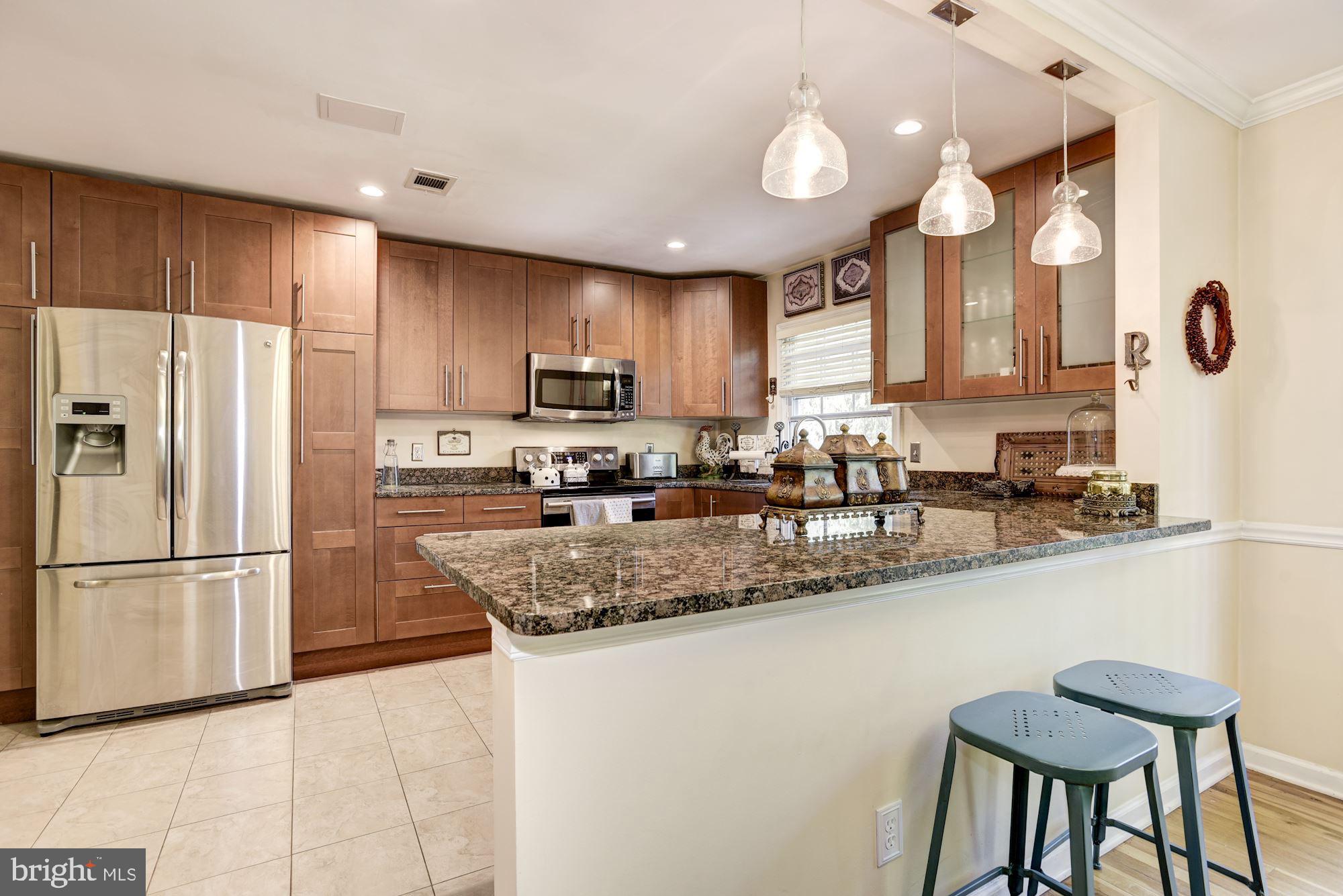 1851 Wainwright Drive Reston, VA 20190 - Photo 8 of 26 a kitchen with stainless steel appliances granite countertop a refrigerator a sink a stove a dining table and chairs