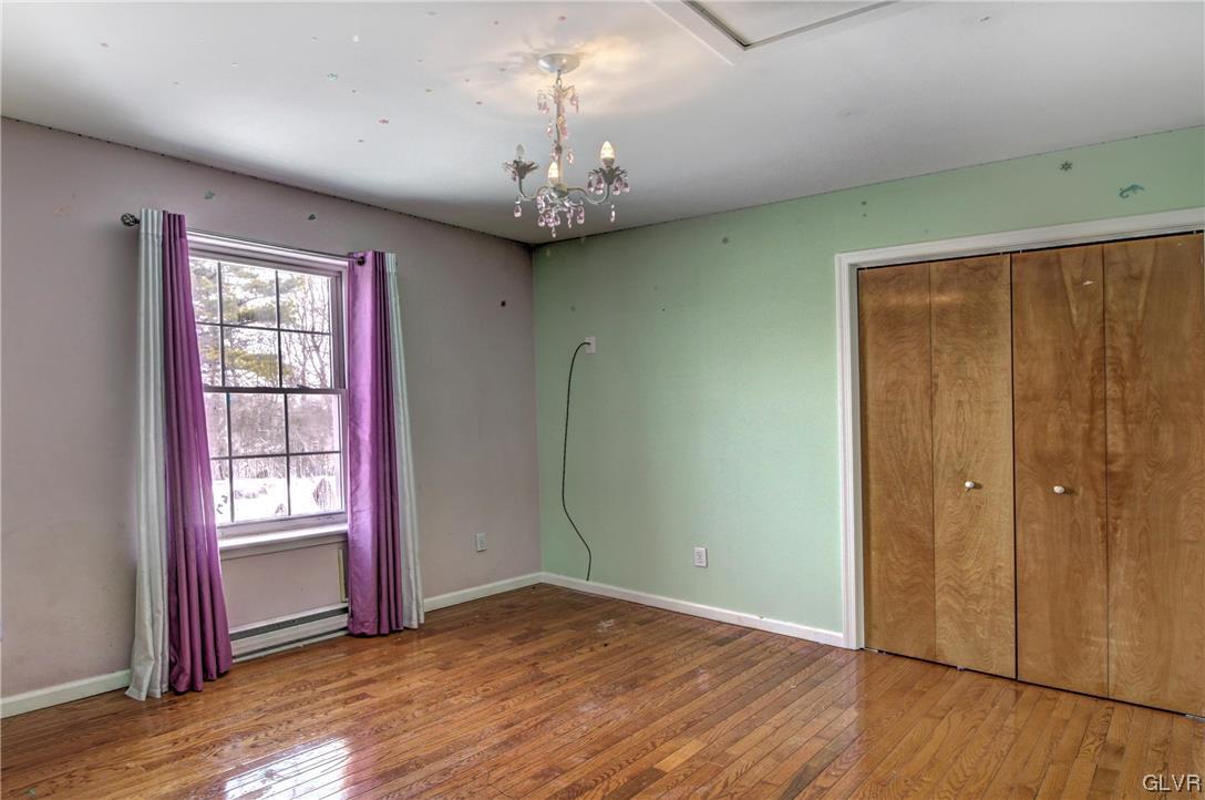1095 Clover Road South Long Pond, PA 18334 - Photo 25 of 27 an empty room with wooden floor chandelier and windows
