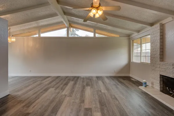 an empty room with wooden floor fireplace and windows