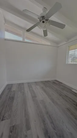 an empty room with a ceiling fan and window
