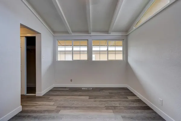 an empty room with wooden floor and a ceiling fan