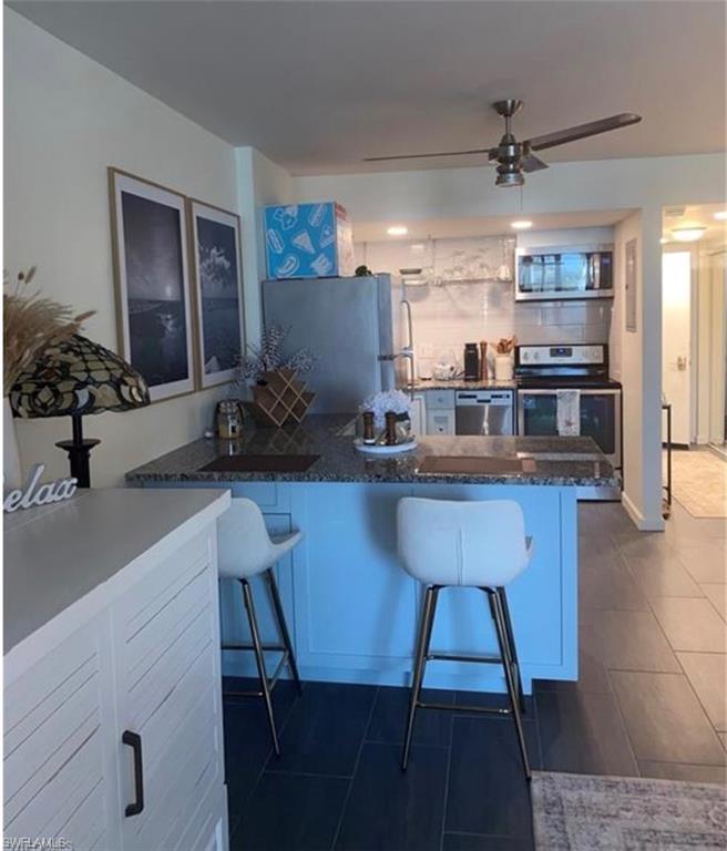 3 Bluebill Avenue, Unit 211 Naples, FL 34108 - Photo 6 of 8 a kitchen with a table chairs refrigerator and microwave