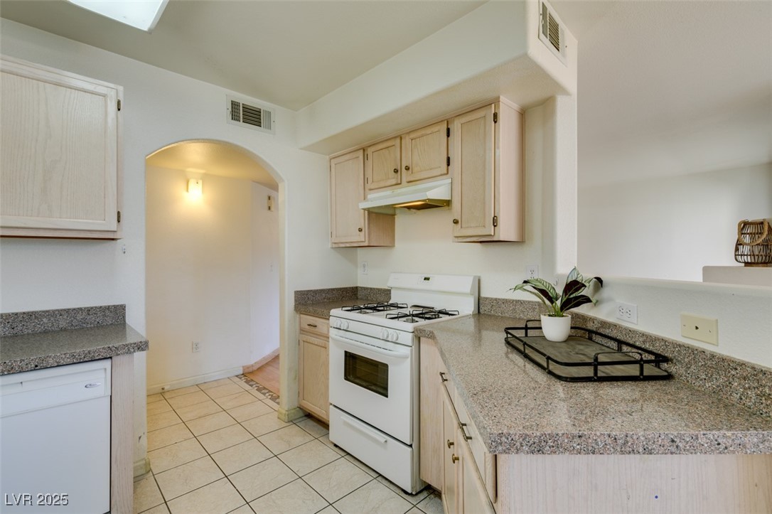 698 South Racetrack Road, Unit 711 Henderson, NV 89015 - Photo 11 of 25 Kitchen featuring white appliances, under cabinet range hood, arched walkways, light tile patterned flooring, and light brown cabinets